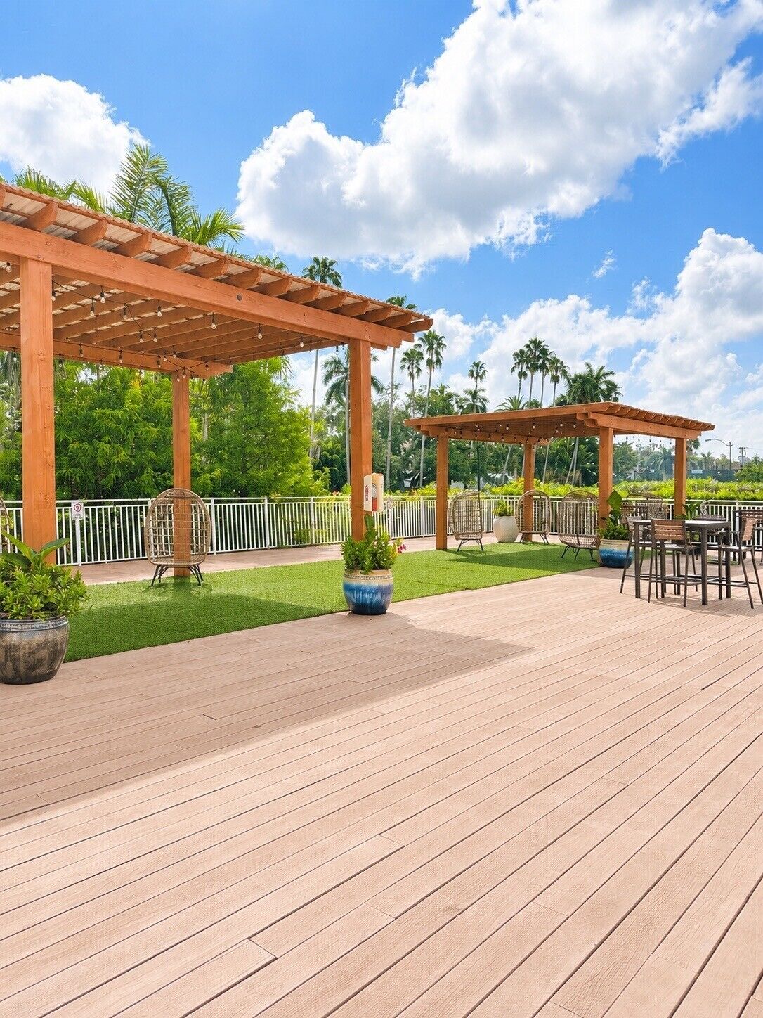 En træterrasse med udendørs møbler og en pergola.