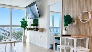 A spacious living area with a large window, a flat-screen TV, and a wooden accent wall. - Waterfront Retreat in Downtown Fort Myers (Fort Myers)