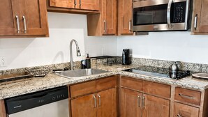 A modern kitchen with wooden cabinets, a stainless steel microwave, a dishwasher, and granite countertops. - Waterfront Retreat in Downtown Fort Myers (Fort Myers)