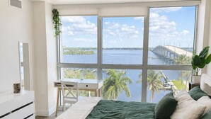 A bedroom with a large window, a bed, a desk, and a chair. - Waterfront Retreat in Downtown Fort Myers (Fort Myers)