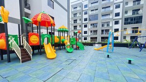A playground with slides and climbing structures, surrounded by a building with balconies. - Modern & Stylish Home (Nairobi)
