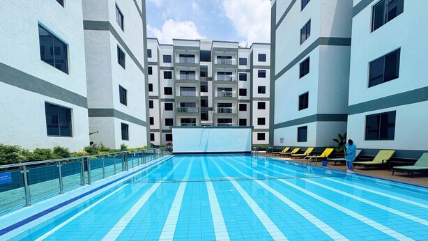 A swimming pool with blue and white tiles, surrounded by a building with multiple balconies and windows. - Modern & Stylish Home (Nairobi)