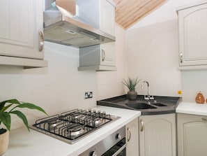 Cozinha com fogão a gás, pia, armários e ventilador de teto.