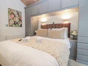Ein ordentlich bezogenes Bett mit einer leopardmusterigen Decke, einem mit integrierter Beleuchtung versehenen Kopfteil und einem Gemälde an der Wand.