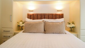A bed with a headboard, two bedside tables with vases, and a wardrobe above. - Fox Red Retreat (Windermere)