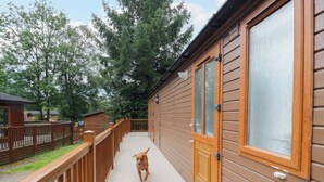 A wooden deck leading to a building with large windows and a door. - Fox Red Retreat (Windermere)