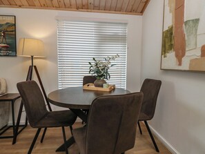 Ein Essbereich mit einem runden Tisch, vier Stühlen, einer Vase mit Blumen und einer Lampe.