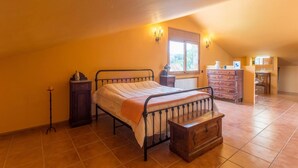 Een slaapkamer met een bed, een dressoir, een nachtkastje en een raam met uitzicht.