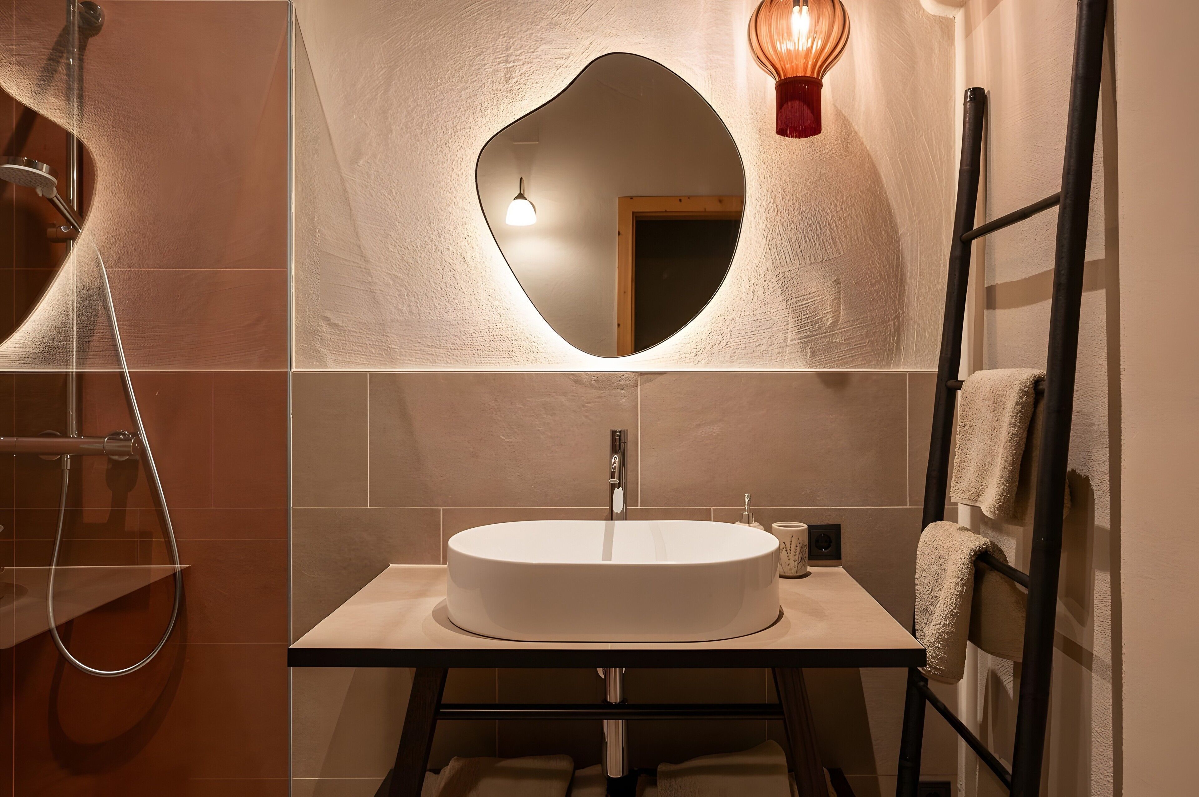 A bathroom with a round sink, a mirror, a towel rack, and a shower.