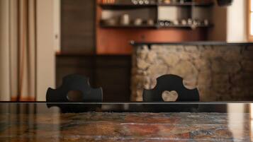 A kitchen with a stone backsplash, a black countertop, and a chair with a heart-shaped cutout.