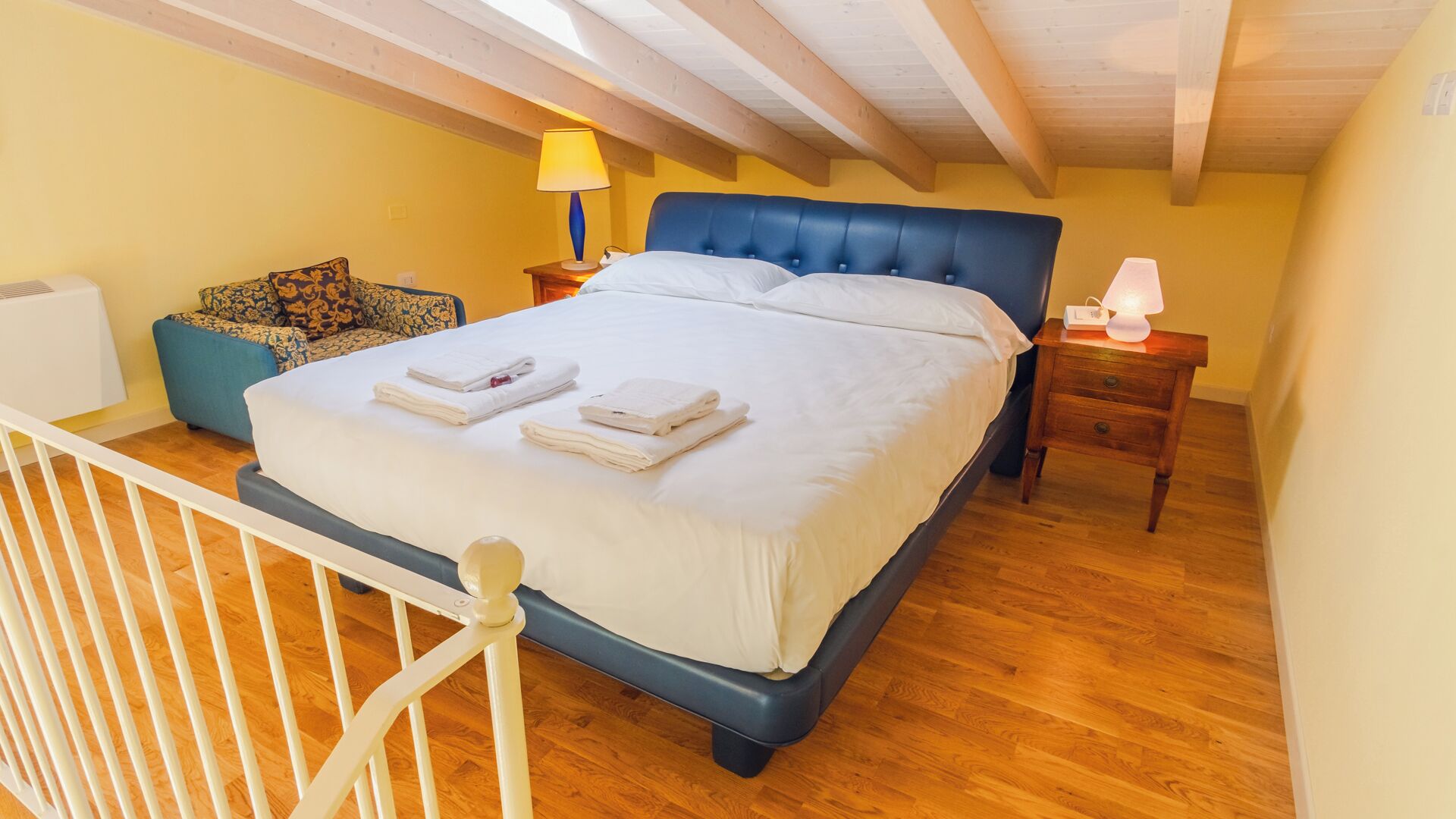 A bedroom with a bed, bedside tables, a lamp, and a chair.