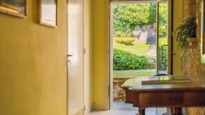 Una porta aperta che dà su un giardino con una fontana, un muro in pietra e una panchina di legno.