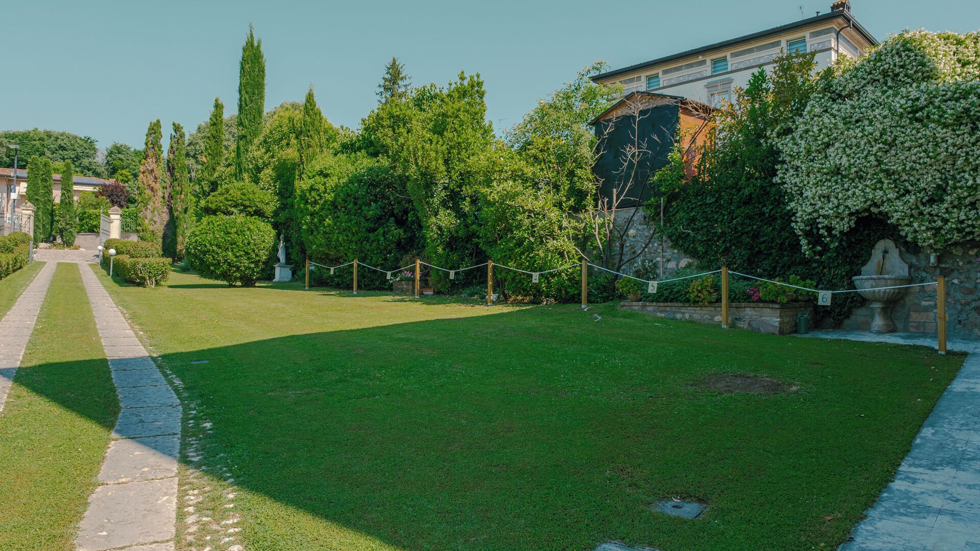 Une pelouse bien entretenue, avec un chemin de pierres menant à un bâtiment.