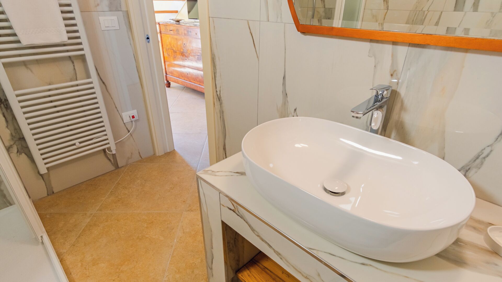 Un baño con lavamanos blanco, un espejo y un perchero para toallas.