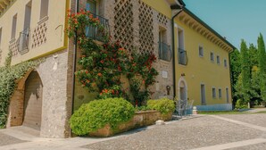 Un edificio de fachada de piedra y exterior amarillo, con un patio y un sendero adoquinado.