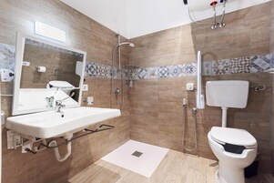 Un baño con lavamanos, espejo, ducha, inodoro y paredes con azulejos.