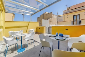 A rooftop terrace with outdoor seating, a glass ceiling, and a view of surrounding buildings. - B&B La Dimora Di Poseidone (Aspra)