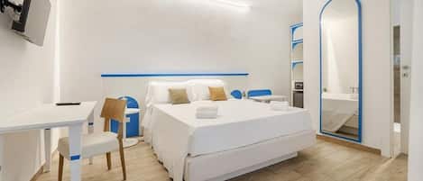 A modern hotel room with a bed, desk, chair, and a large mirror.