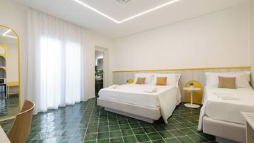 A hotel room with a large bed, a smaller bed, a round table, and a mirror.