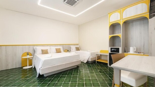 Una habitación de hotel con cama, una mesita, una silla y un armario.