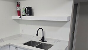 Eine Küche mit doppelter Spüle, weißen Schränken, einem schwarzen Wasserhahn und einem Regal über der Spüle.