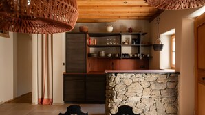 A modern kitchen with a stone island, wooden cabinets, and hanging baskets. - Apartment 'Kailash - Juval Oberortlhof' with Mountain View and Wi-Fi (Juvale)