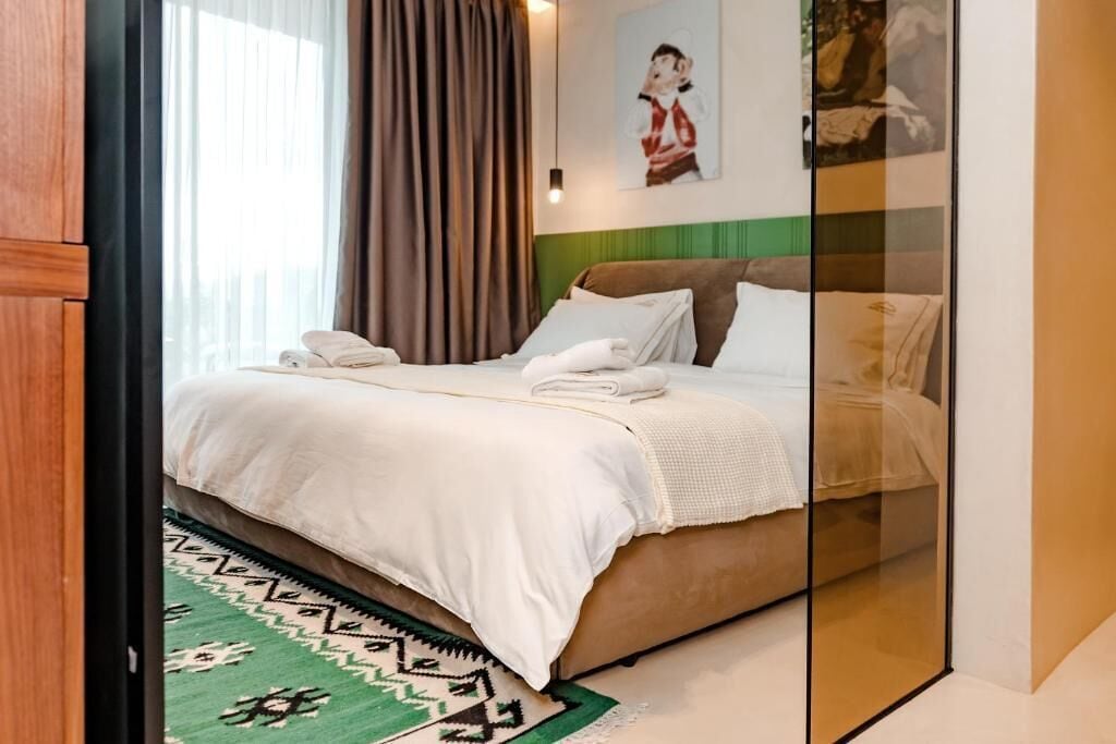 Una habitación de hotel con una cama, un tapete de diseño verde y un cuadro en la pared.