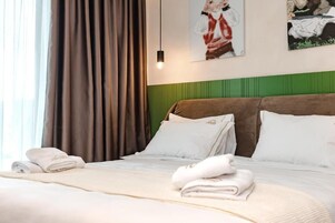 A hotel room with a bed, pillows, a blanket, and a painting on the wall.