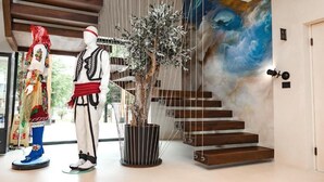 Una escalera de diseño moderno, un maniquí vestido con traje tradicional y un árbol en maceta.