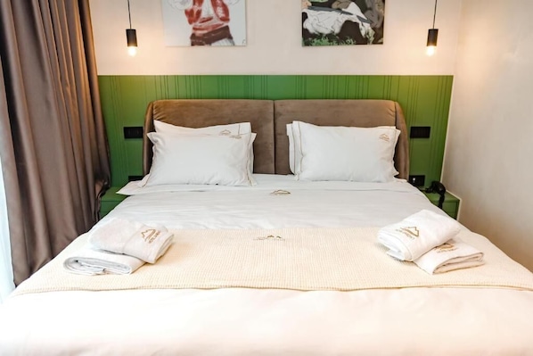 A double bed with a green headboard, white bedding, and two bedside tables with lamps. - Hotel Dardan (Bajram Curri)