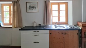 A kitchen with a wooden beam ceiling, a window with curtains, a sink, and a framed picture on the wall. - Apartment 'Cho Oyu - Juval Oberortlhof' with Mountain View and Wi-Fi (Juvale)