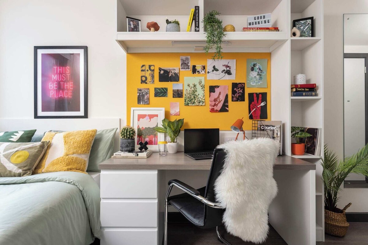 A modern bedroom with a bed, desk, and shelves.