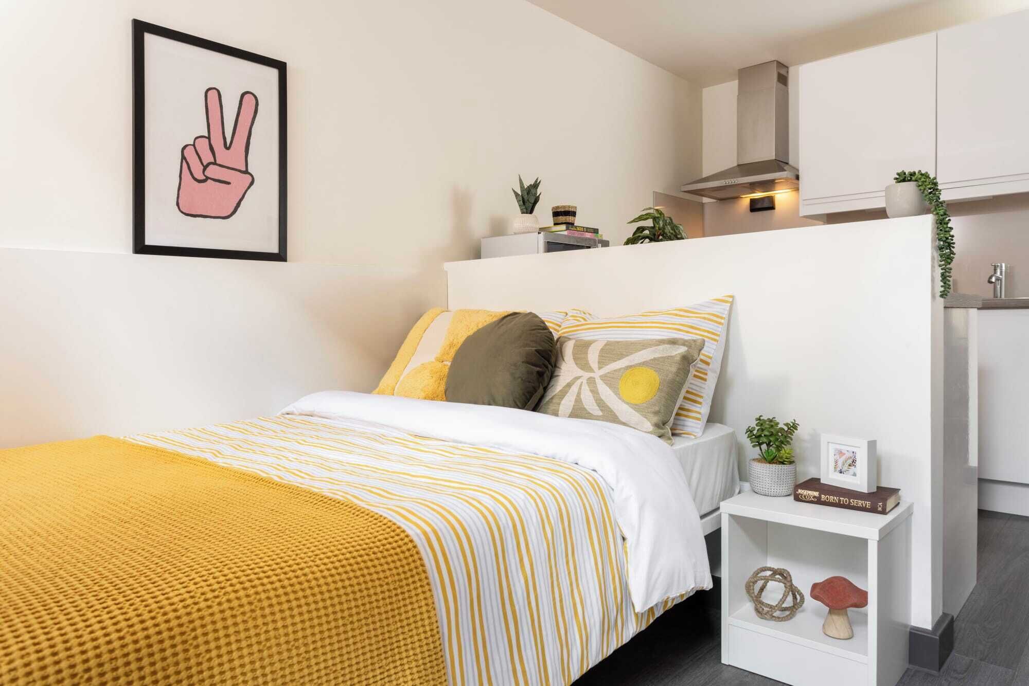 A neatly arranged bedroom with a bed, bedside table, and a framed picture on the wall.