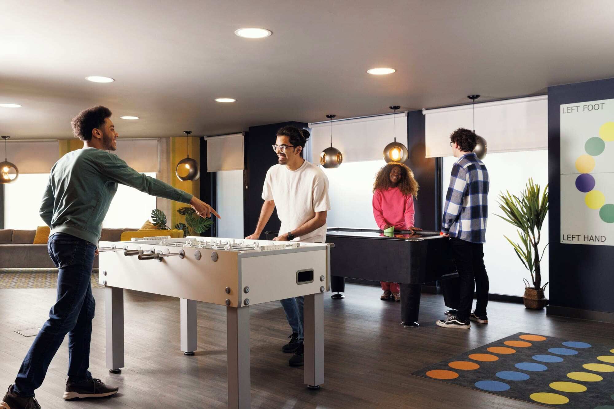 A modern indoor space with a foosball table, a foosball table, and a foosball table.