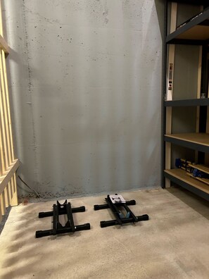 Ein Zimmer mit einer Betonwand, Holzboden und einem Metallregal mit Gegenständen darauf.