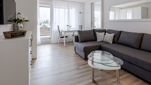 A modern living room with a sofa, a glass coffee table, and a dining area with a table and chairs. - Alexandra 513 Appartement/Fewo, Dusche, WC, 2-Bettwohnung by Interhome (Arosa)