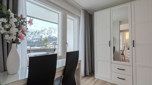 A room with a desk, two chairs, a large wardrobe, a mirror, and a view of mountains. - Alexandra 513 Appartement/Fewo, Dusche, WC, 2-Bettwohnung by Interhome (Arosa)