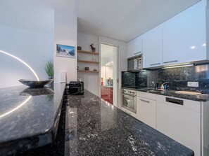 A modern kitchen with a black granite countertop, stainless steel appliances, and white cabinetry. - Alexandra 513 Appartement/Fewo, Dusche, WC, 2-Bettwohnung by Interhome (Arosa)