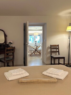 A hotel room with a bed, a desk with a mirror, two chairs, a dining table with chairs, and a lamp. - Casa Verde Minimal Cozy Stay (Elliniko-Argyroupoli)