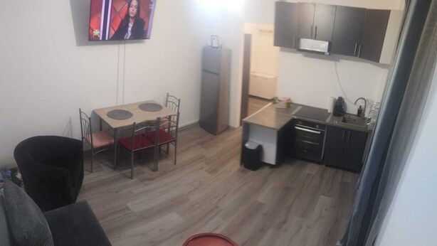 A compact living space with a dining area, kitchenette, and a TV mounted on the wall.