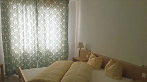 A single-bed room with a wooden headboard, a bedside table with a lamp, and a patterned curtain. - Les Naturelles B 106 # 5-bed apartment, Dusche und Bad, WC by Interhome (Leukerbad)