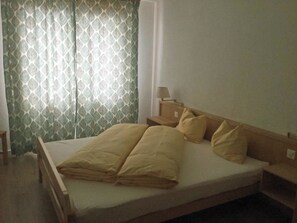 A single-bed room with a wooden headboard, a bedside table with a lamp, and a patterned curtain. - Les Naturelles B 106 # 5-bed apartment, Dusche und Bad, WC by Interhome (Leukerbad)