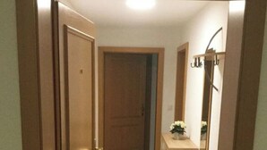 A hallway with a wooden door, a tiled floor, a wooden cabinet, and a mirror. - Les Naturelles B 106 # 5-bed apartment, Dusche und Bad, WC by Interhome (Leukerbad)