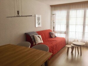 A living room with a wooden table, a red sofa, two chairs, and a floor lamp. - Les Naturelles B 106 # 5-bed apartment, Dusche und Bad, WC by Interhome (Leukerbad)
