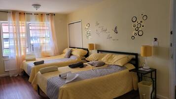 A hotel room with two beds, a bedside table with a lamp, a wall decoration, and a window with curtains.