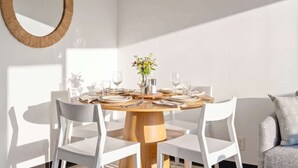 Una mesa redonda para comer con sillas blancas, un centro de mesa de madera y un espejo en la pared.