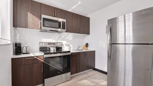 Una cocina moderna con armarios de madera oscura, electrodomésticos de acero inoxidable y un microondas integrado.