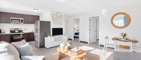 A modern apartment with a kitchen, living room, dining area, and a bedroom.