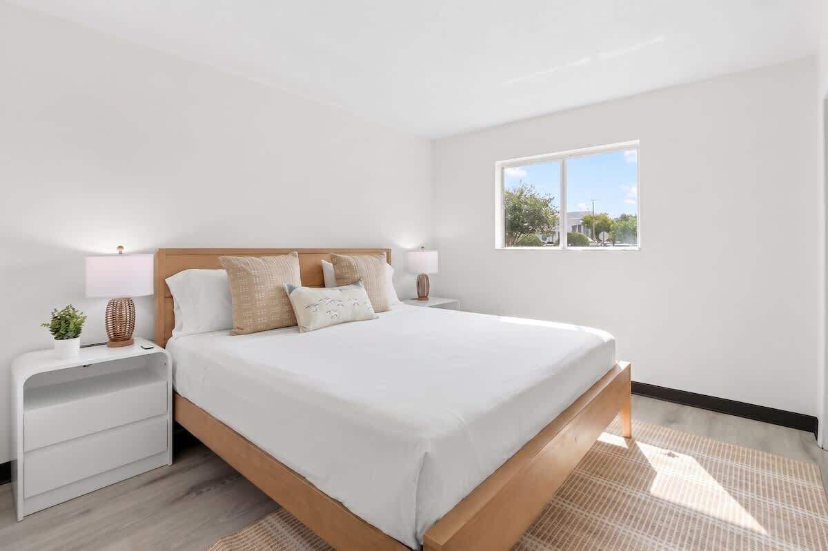 Une chambre à coucher avec un lit, des tables de chevet, une fenêtre et une vue sur l’extérieur.