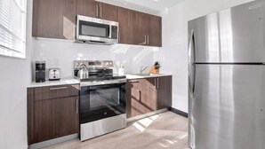 Eine moderne Küche mit Edelstahlgeräten, dunklen Holzschränken und einem großen Kühlschrank.